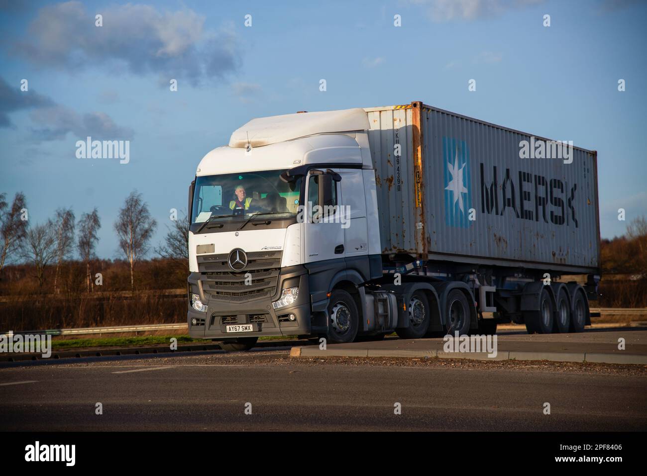 A Mercedes-Benz Actros truck pulling a trailer with a Maersk shipping container, crosses a roundabout in front of iPort near Doncaster Stock Photo