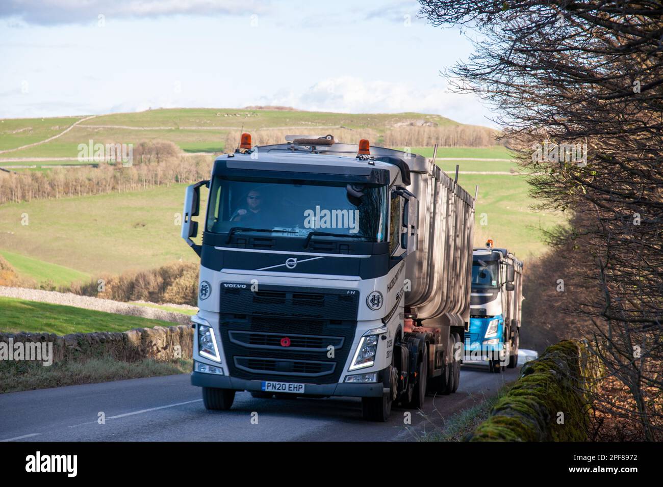 A Volvo truck pullling a bulk tipper trailer climbing the hill from Tunstead Quarry in Derbyshire Stock Photo