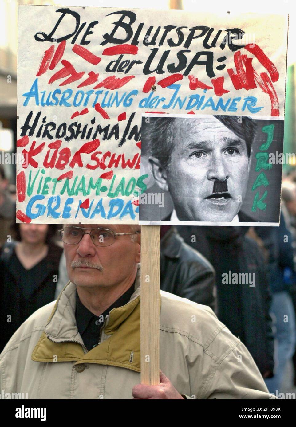 An unidentified man carries a banner with a portrait of U.S. President Bush made up to resemble Adolf Hitler during a demonstration in the city of Leipzig, eastern Germany, Monday, March 24, 2003. Hundreds of people gathered for a peace rally against the war in Iraq after a peace prayer in the St. Nikolai church. The protest march took place in the tradition of the "Monday demonstrations" of 1989, which finally led to the peaceful revolution in former East Germany. The banner reads: "The Blood trail ofthe USA - Eradication of Indians, Hiroshima, Cuba/ Bay of Pigs, Vietnam, Grenada..." (AP Phot Stock Photo