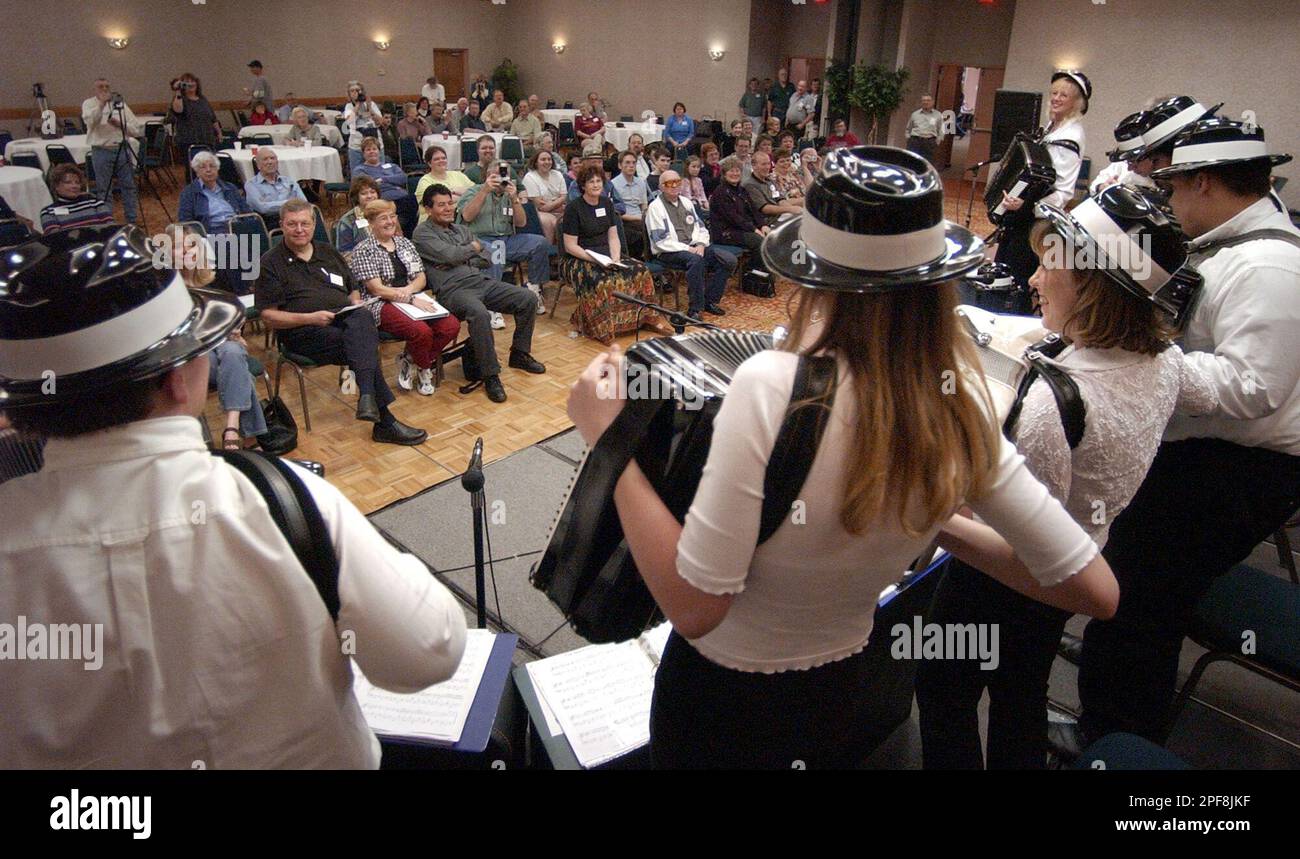 Members of an accordion youth band stand and dance as they play a tune