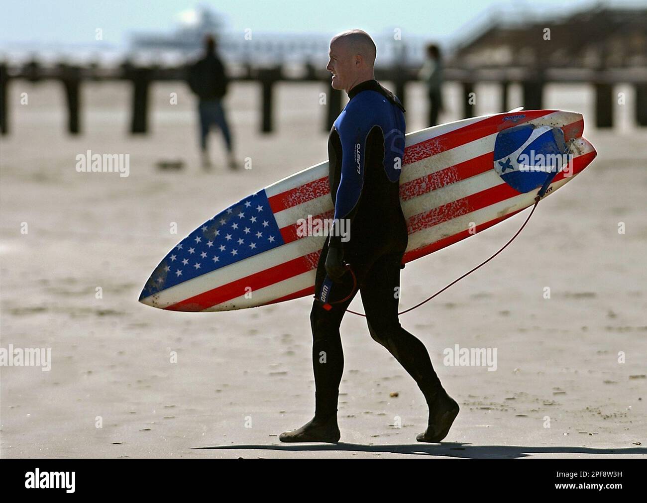 Brett Newman of James Island S.C. walks to the surf at the Washout on Folly Beach S.C. Sunday Feb. 23 2003. Newman said he has the patriotic surfboard because he works for