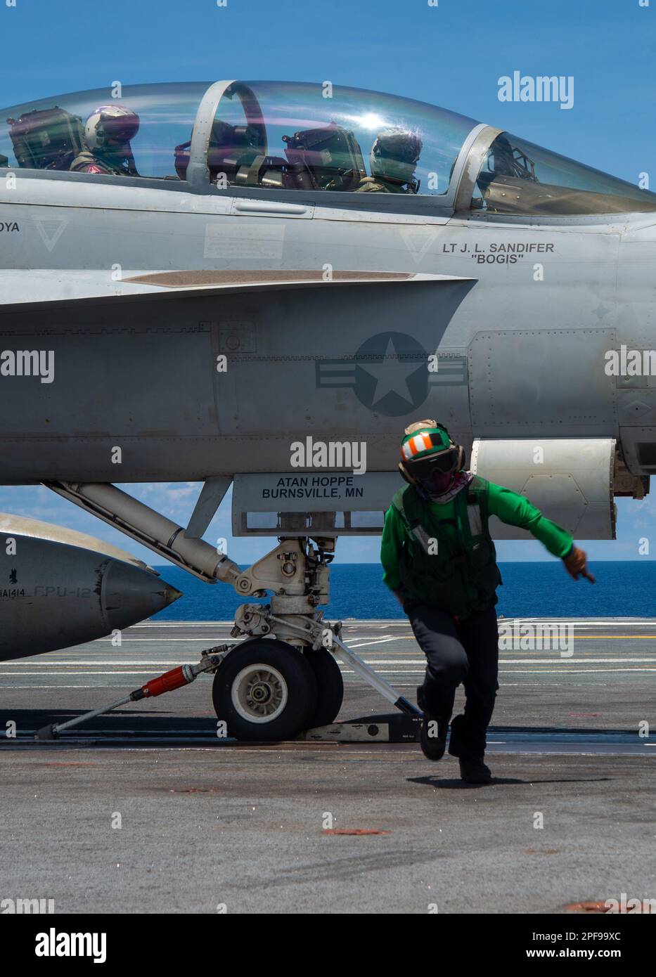 230315-N-WM182-1039 PHILIPPINE SEA (March 15, 2023) A U.S. Navy Sailor moves away from an F/A-18F Super Hornet from the “Fighting Redcocks” of Strike Fighter Squadron (VFA) 22 before launch on the flight deck of the aircraft carrier USS Nimitz (CVN 68). Nimitz is in U.S. 7th Fleet conducting routine operations. 7th Fleet is the U.S. Navy's largest forward-deployed numbered fleet, and routinely interacts and operates with Allies and partners in preserving a free and open Indo-Pacific region. (U.S. Navy photo by Mass Communication Specialist 2nd Class Caitlin Flynn) Stock Photo