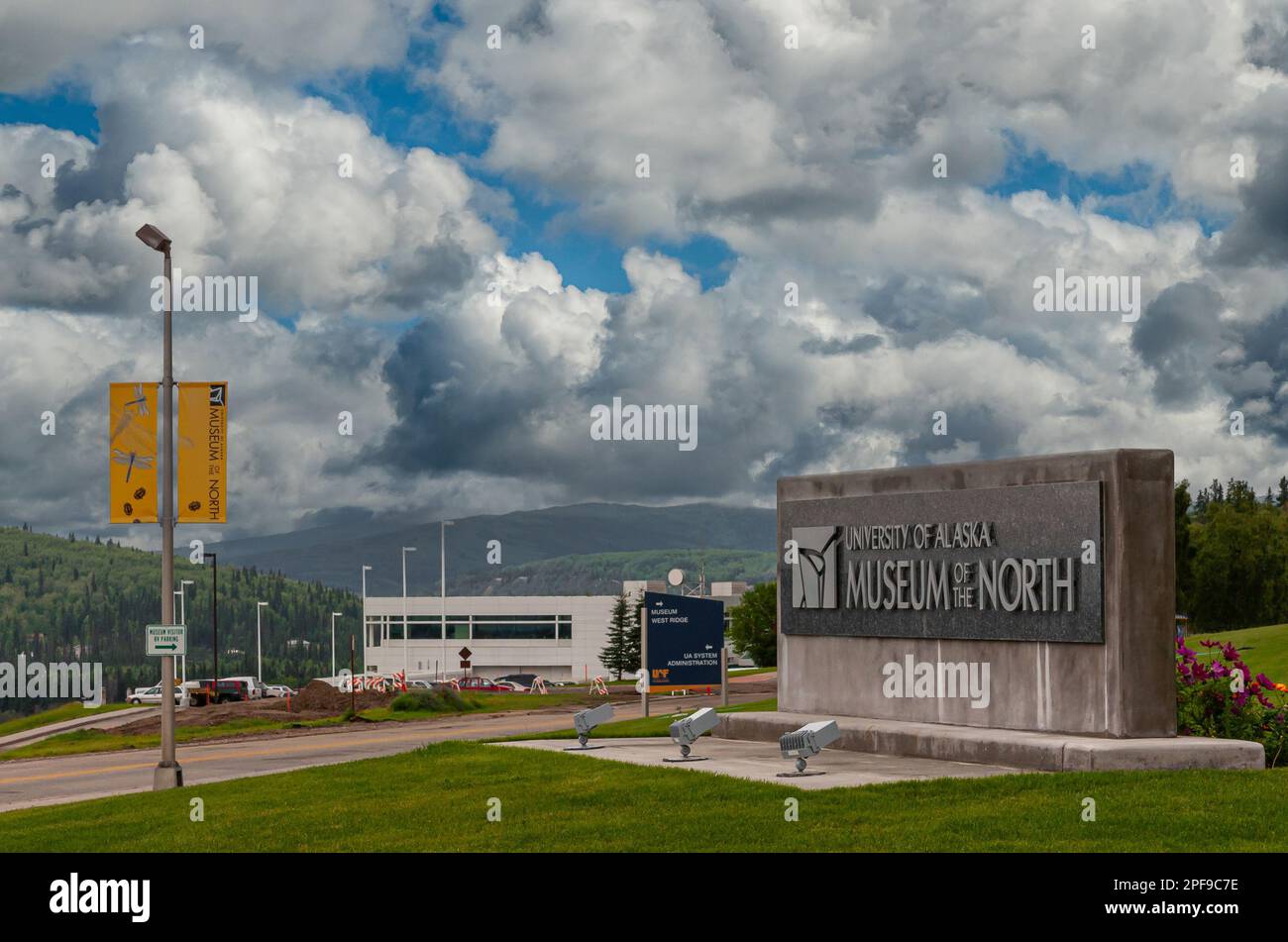 Fairbanks, Alaska, USA - July 27, 2011: University of Alaska main concrete block as name sign at entrance road under thick blue cloudscape. Museum of Stock Photo