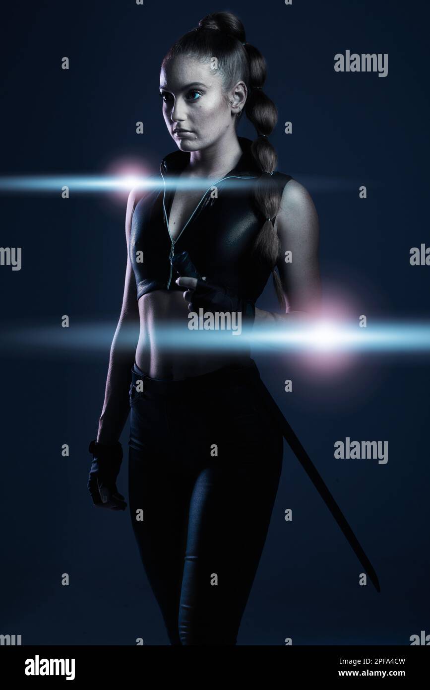 Woman, sword and assassin in studio with costume, action or cyberpunk fashion in suit. Girl, blade and leather fashion for crime, danger and Stock Photo