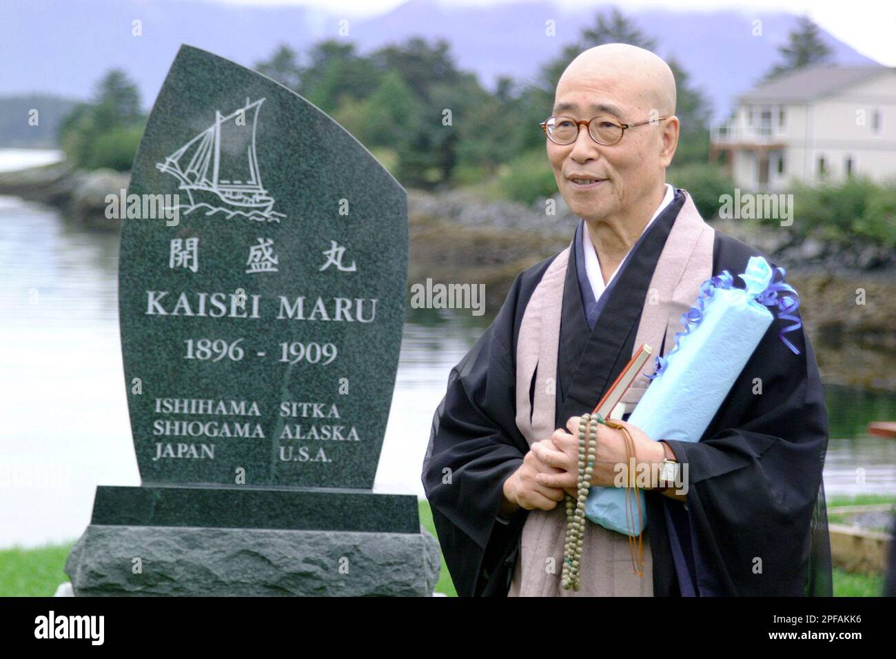 The Rev. Dokan Shoichi Makabe stands next to a granite memorial marker