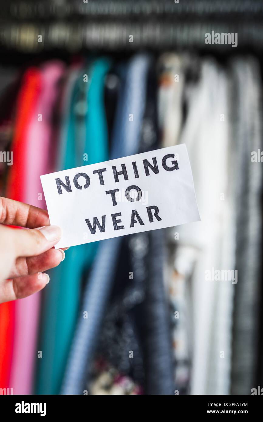 Nothing to Wear sign ironically held in front of wardrobe full of clothes, concept of excessive shopping and consumerism Stock Photo