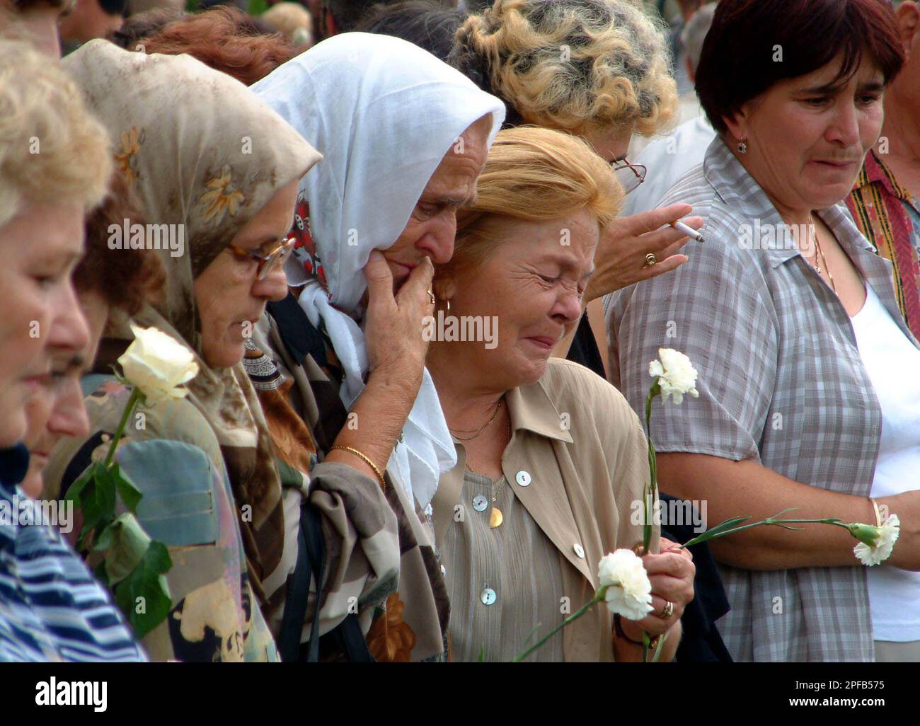 Muslim women praying and crying as they remember loved ones killed during the Bosnian war, at a ceremony in Koricanske Stijene on Wednesday, Aug. 21, 2002. In August 1992, just a few months into Bosnia's 1992-1995 war, Bosnian Serb police forces and paramilitary troops executed 253 non-Serb men by shooting them and pushing them over a cliff into a ravine, located near the town of Travnik, 70 kilometers (40 miles) northwest of Sarajevo. The victims had been prisoners in the notorious Bosnian Serb-run concentration camps Omarska, Keraterm and Trnopolje. Only 12 men are known to have survived. On Stock Photo