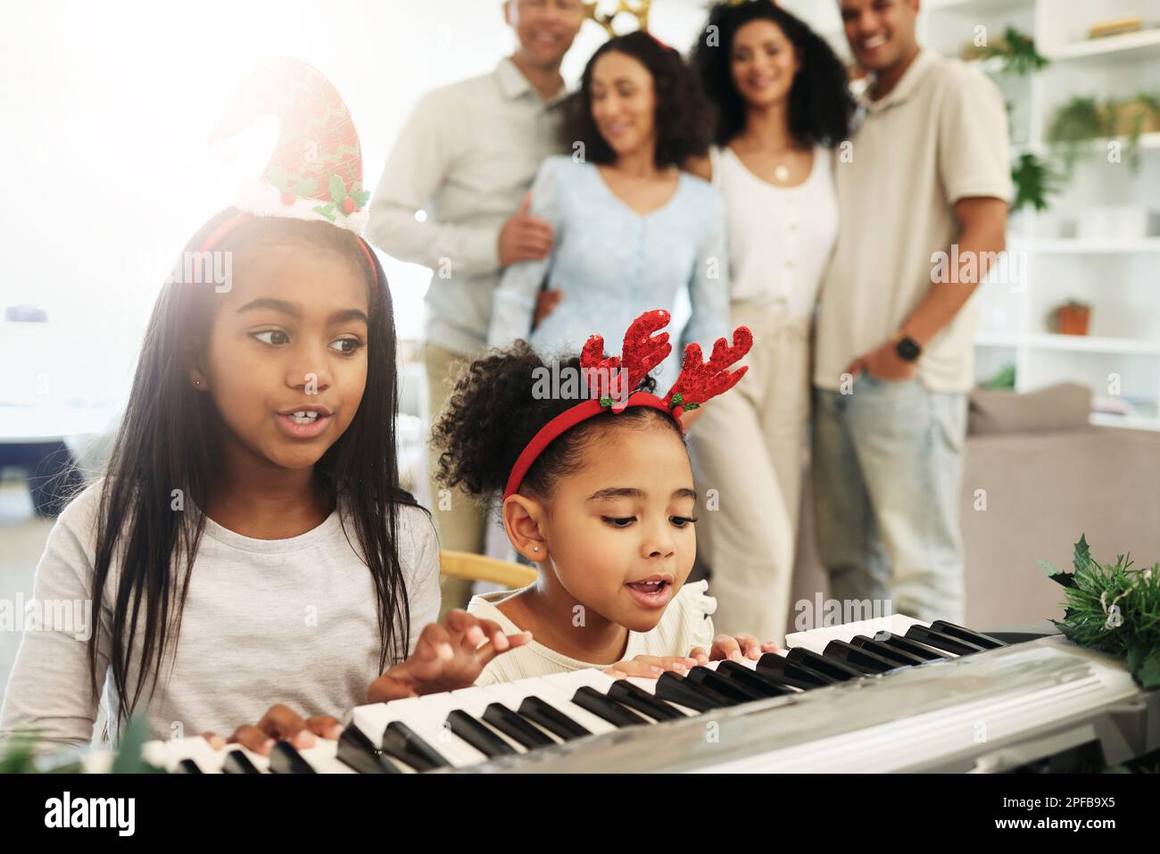 Children, singing and Christmas piano songs on a holiday or vacation excited in a home or house with a happy family. People, celebrate and kids make Stock Photo
