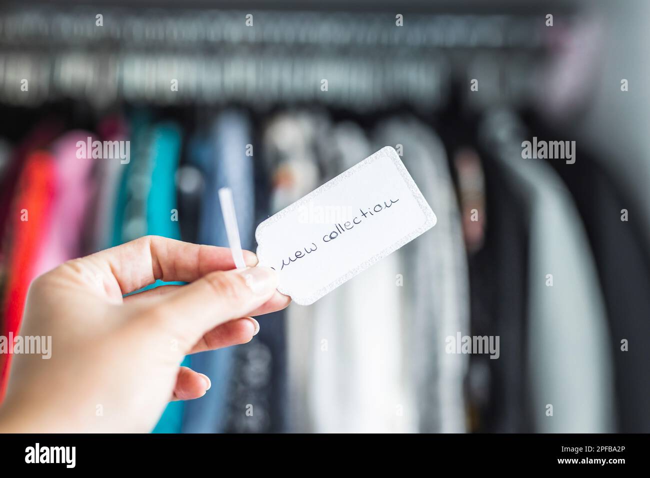 New Collection sign held in front of rack full of clothes, concept of fashion brands and competition Stock Photo