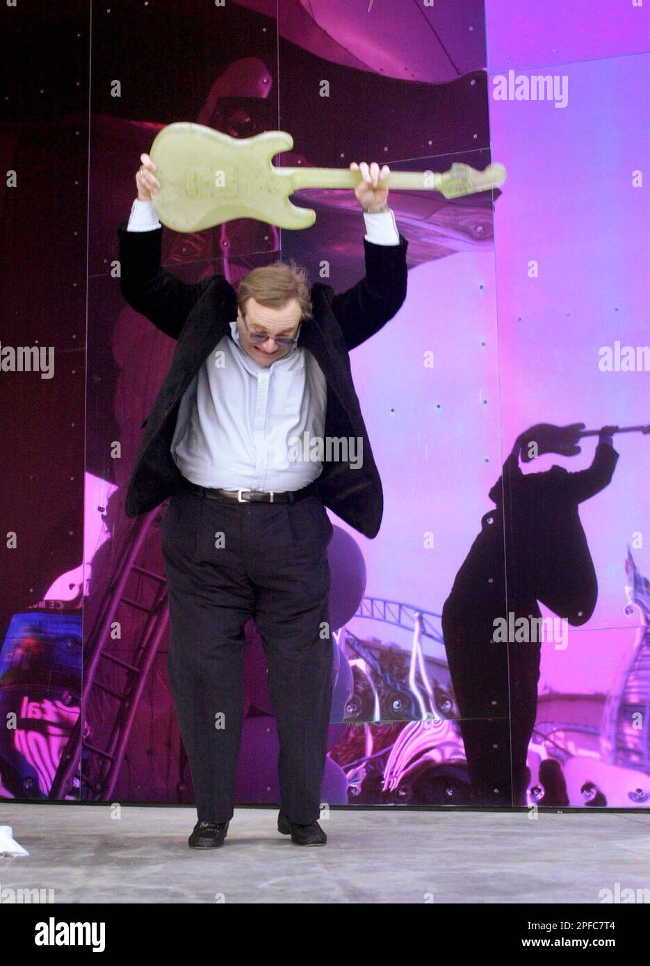 Paul Allen lifts a Dale Chihuly glass guitar above his head before