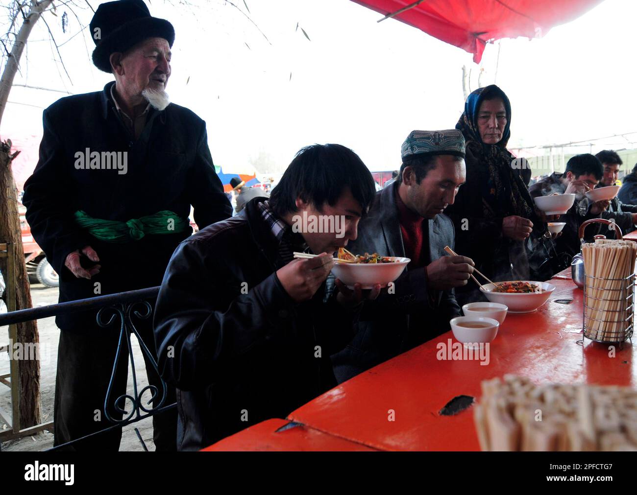 A small roadside restaurant serving Lagman noodles and rice with dumplings at a weekly livestock market in the outskirts of Kashgar, Xinjiang, China. Stock Photo