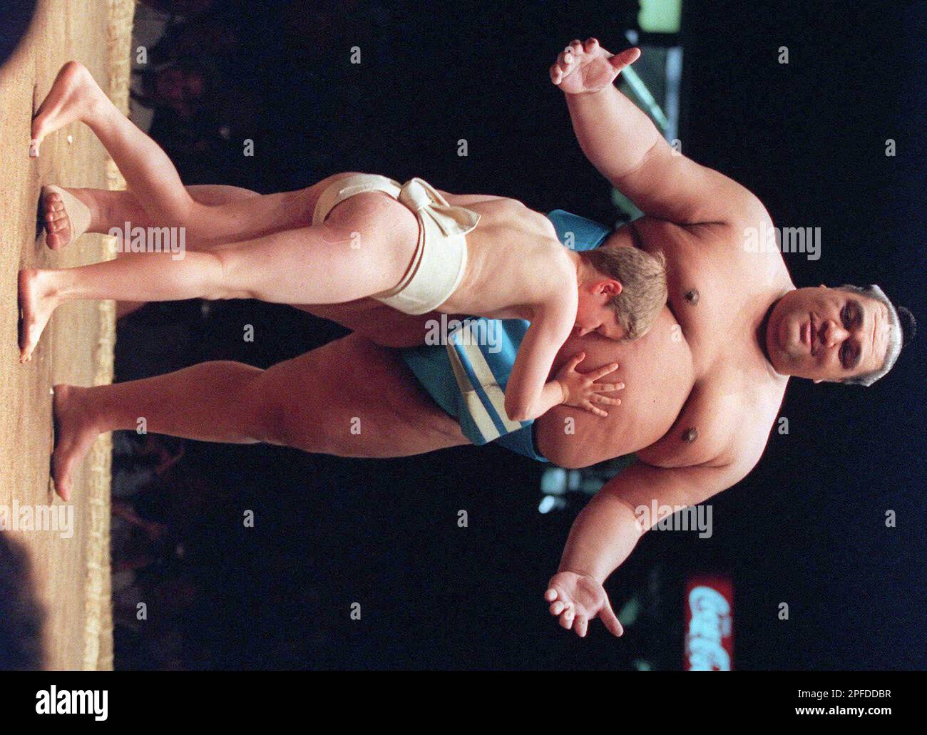 Sumo wrestler Koyo Musashimaru stands his ground as a young enthusiasts engages him in an exhibition match prior to Sumo competition in Vancouver, British Columbia Saturday, June 6, 1998.(AP Photo/Chuck Stoody) Stock Photo