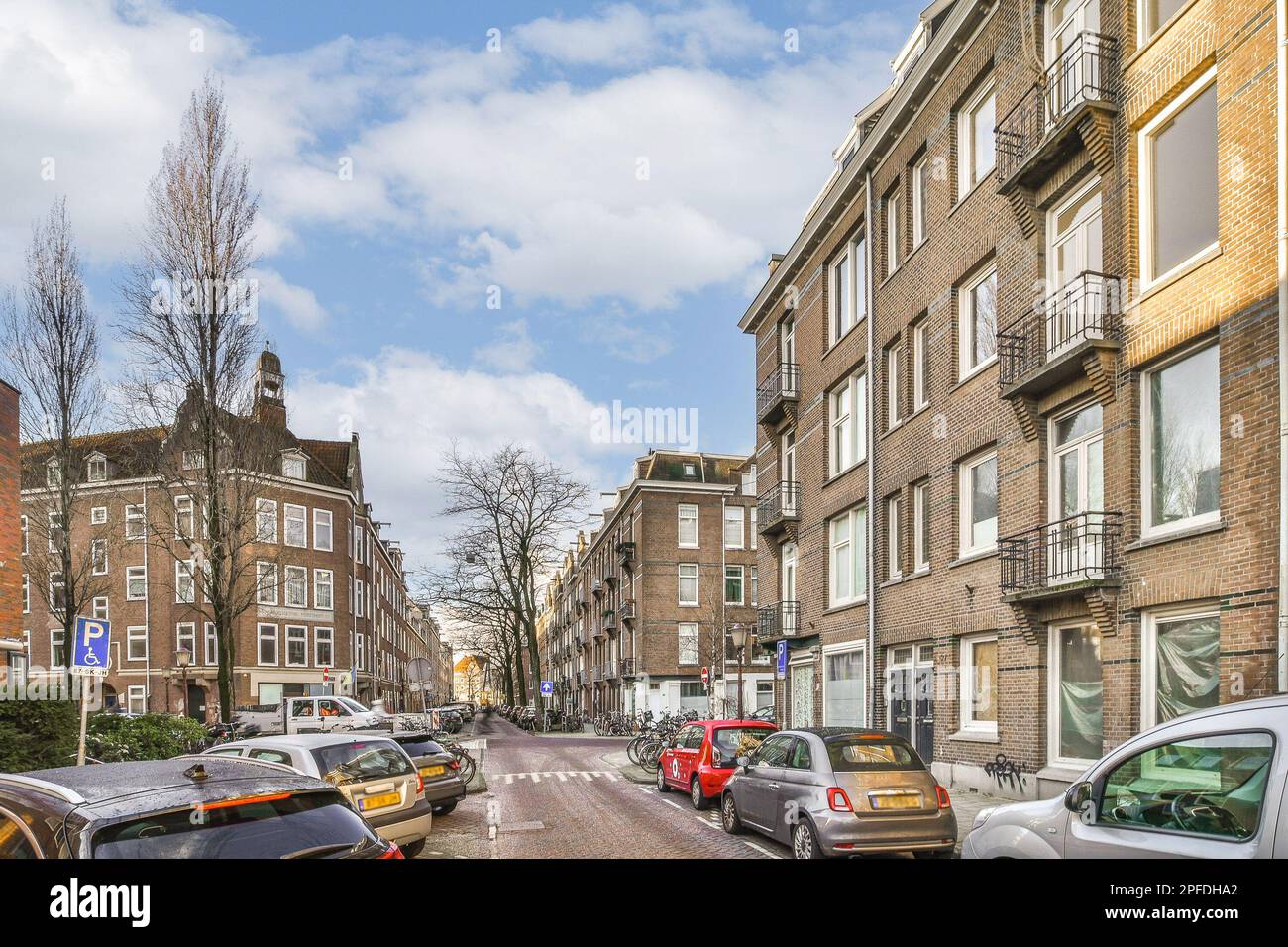 a city street with cars parked on the side and buildings in the back ...