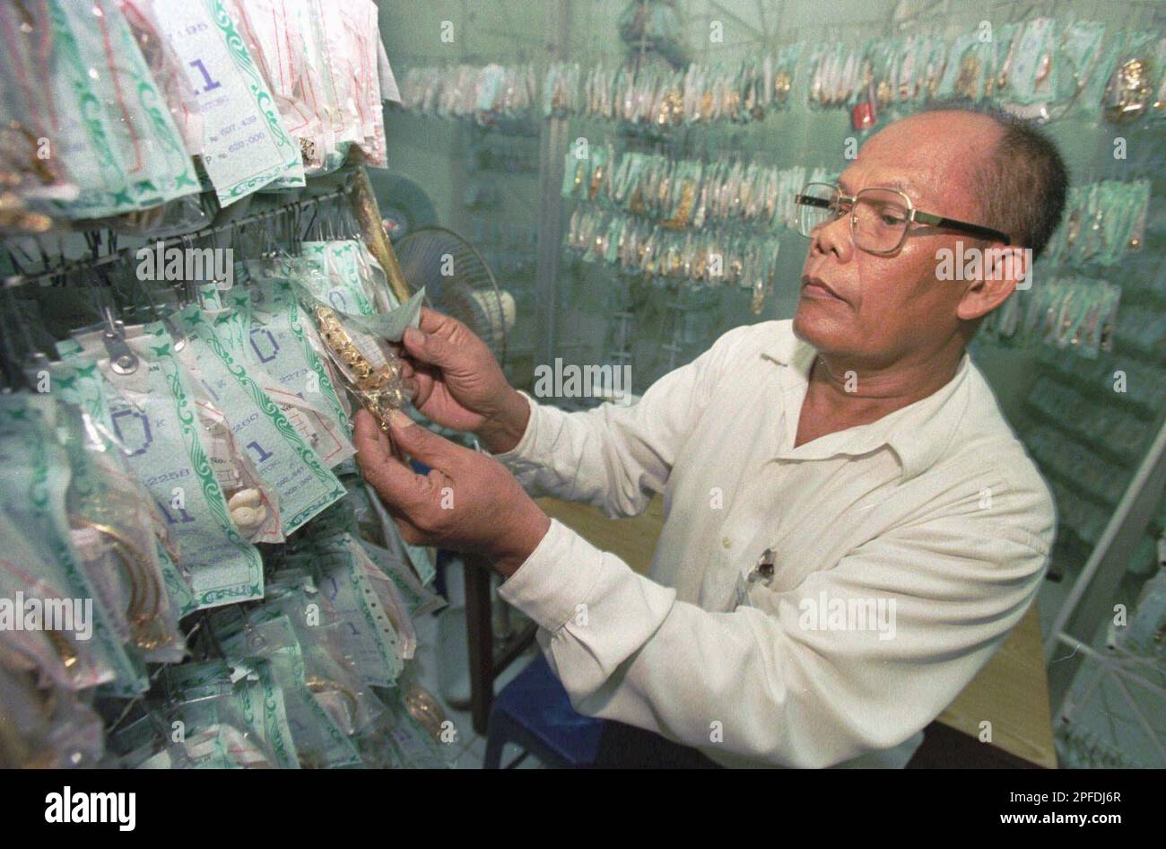 Pawn shop worker Mulyono checks through plastic bags of pawned gold