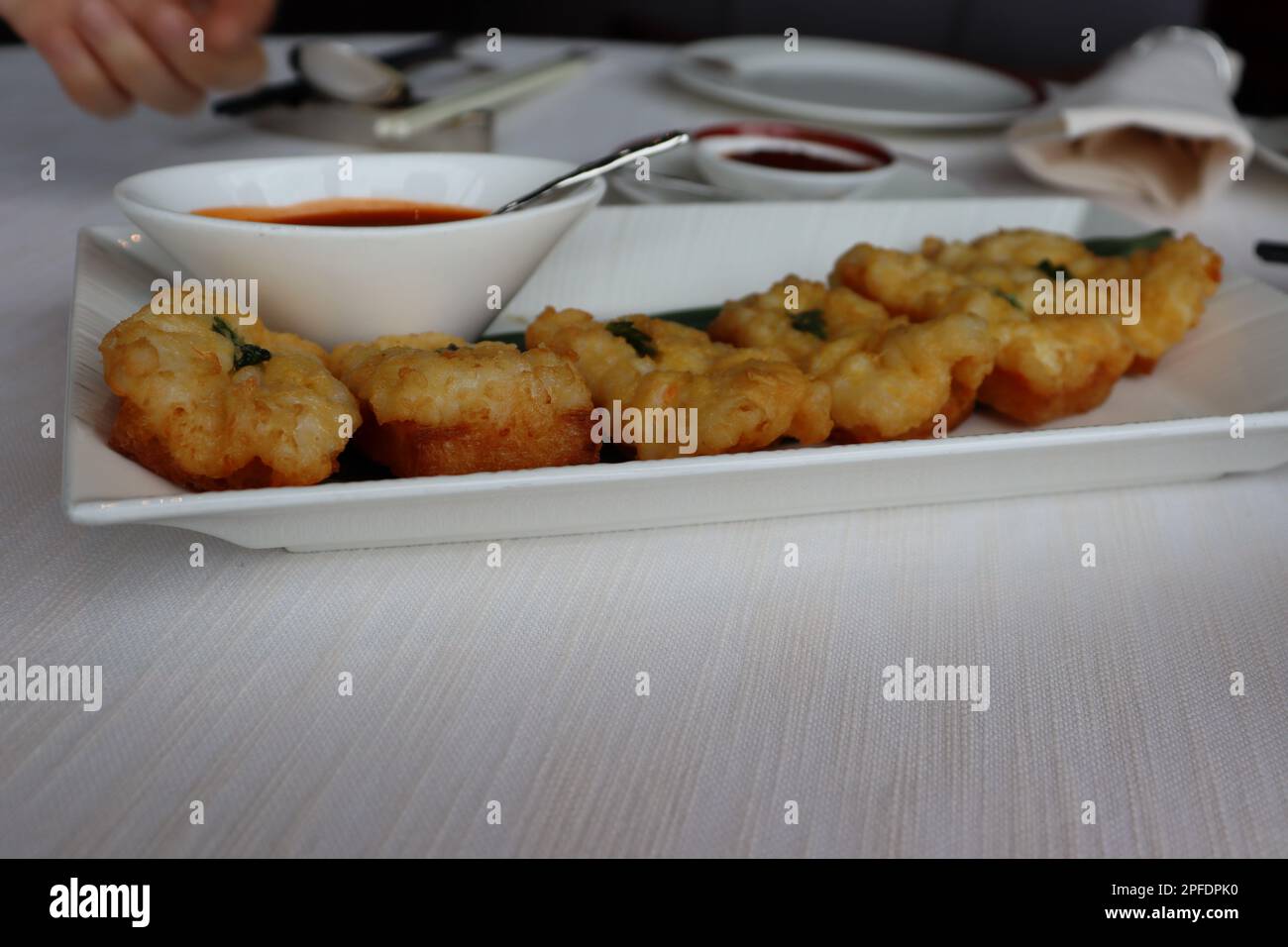 A white plate featuring a selection of crispy deep-fried food, served with a side of dipping sauce Stock Photo