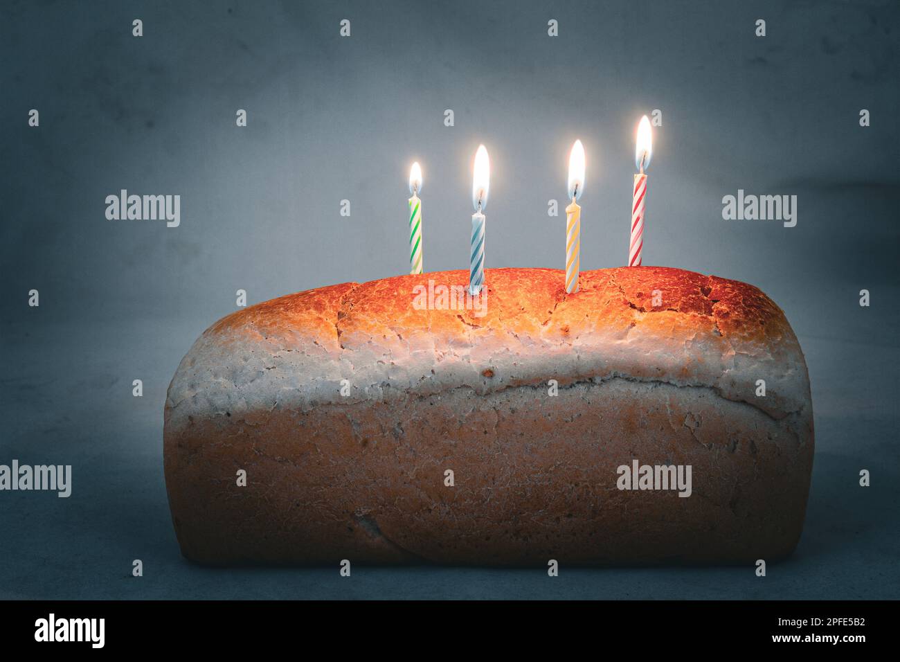 A birthday cake made from a loaf of bread with four party candles Stock