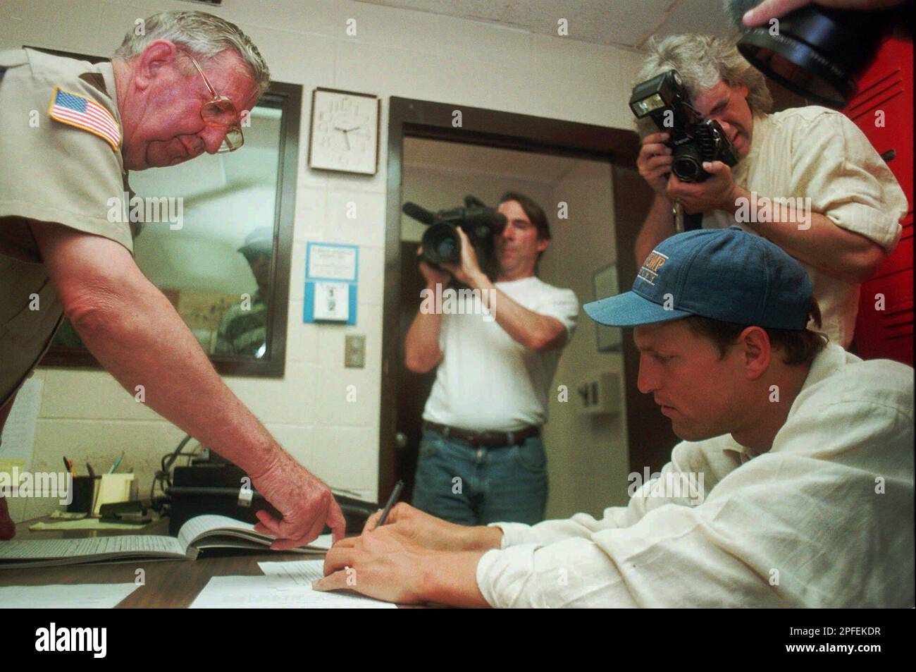 Actor Woody Harrelson, right, signs a form saying that he was read his