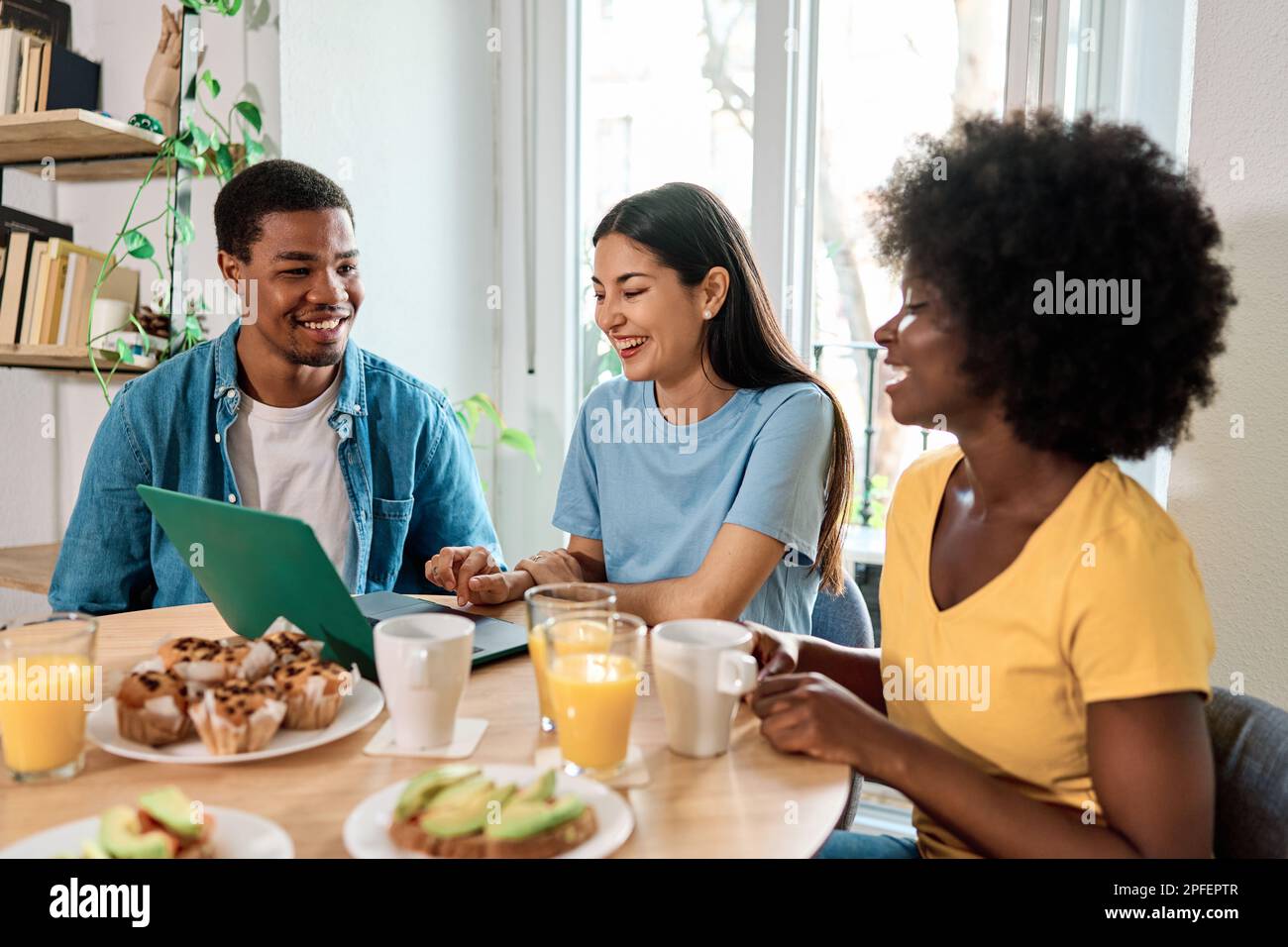 Friends using laptop while having breakfast at home Stock Photo