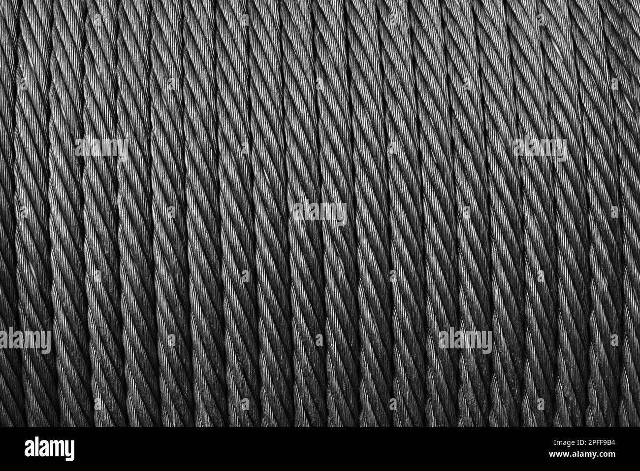 Steel rope is on a winch, close up, abstract industrial background texture. Black and white photo Stock Photo