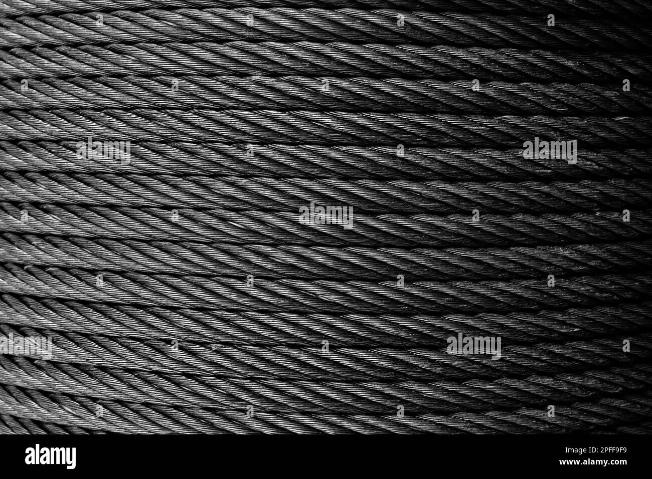 Steel rope is on a winch, abstract industrial background texture. Black and white photo Stock Photo