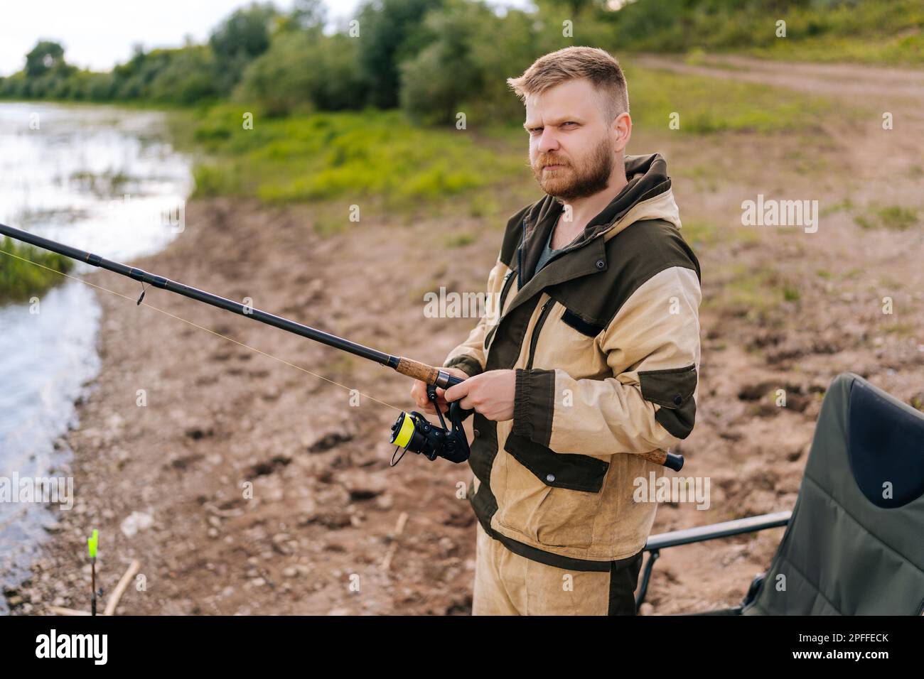 Portrait of bearded fisher man holding spinning casting rod standing on  bank waiting for bites on water river at summer day, looking at camera  Stock Photo - Alamy