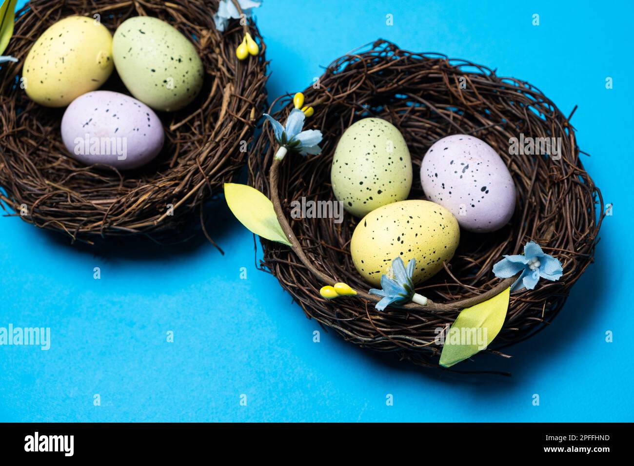 Easter eggs in wicker nest baskets on a blue background Stock Photo