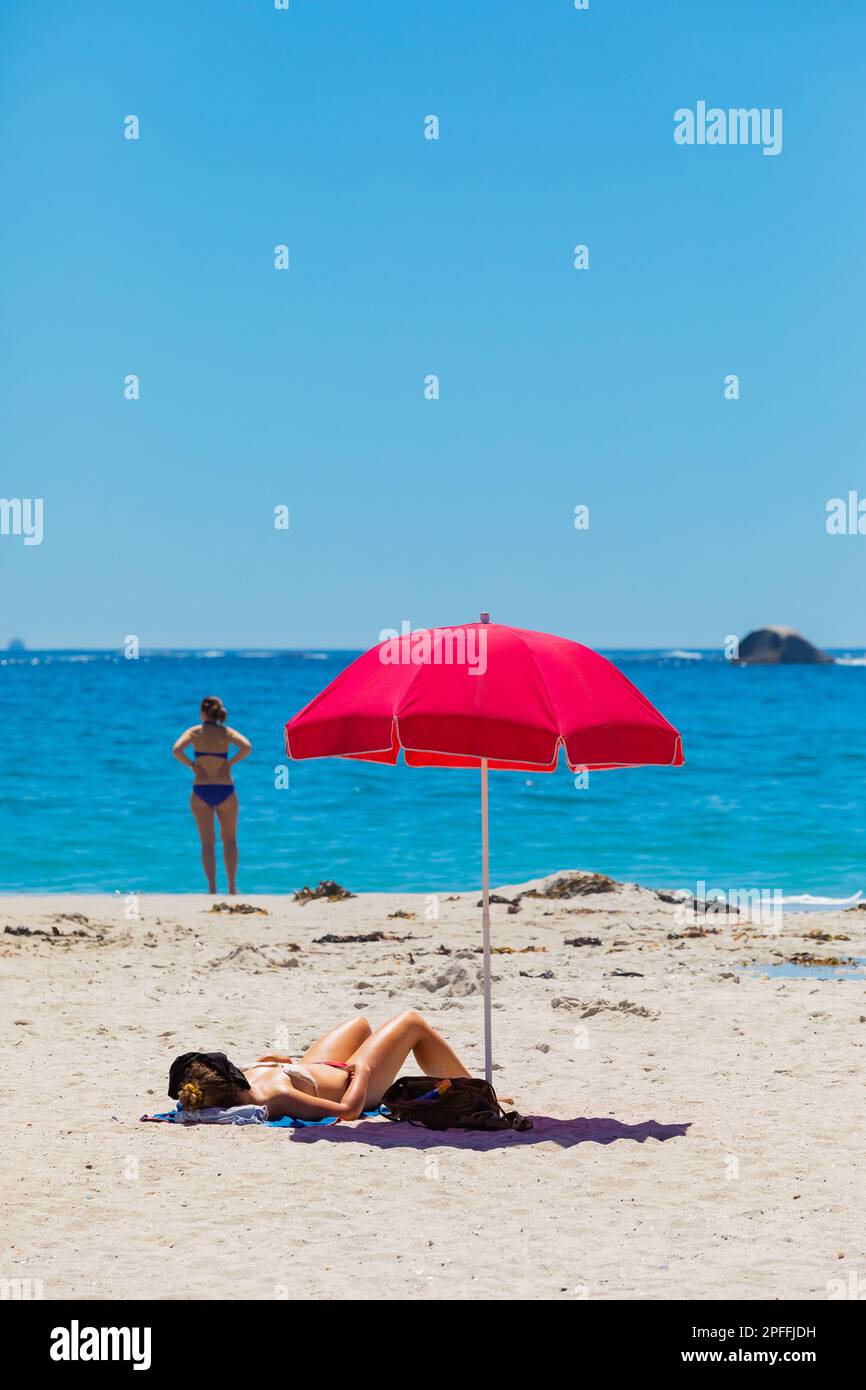 female-vacationers-suntanning-on-sandy-beach-in-camps-bay-cape-town