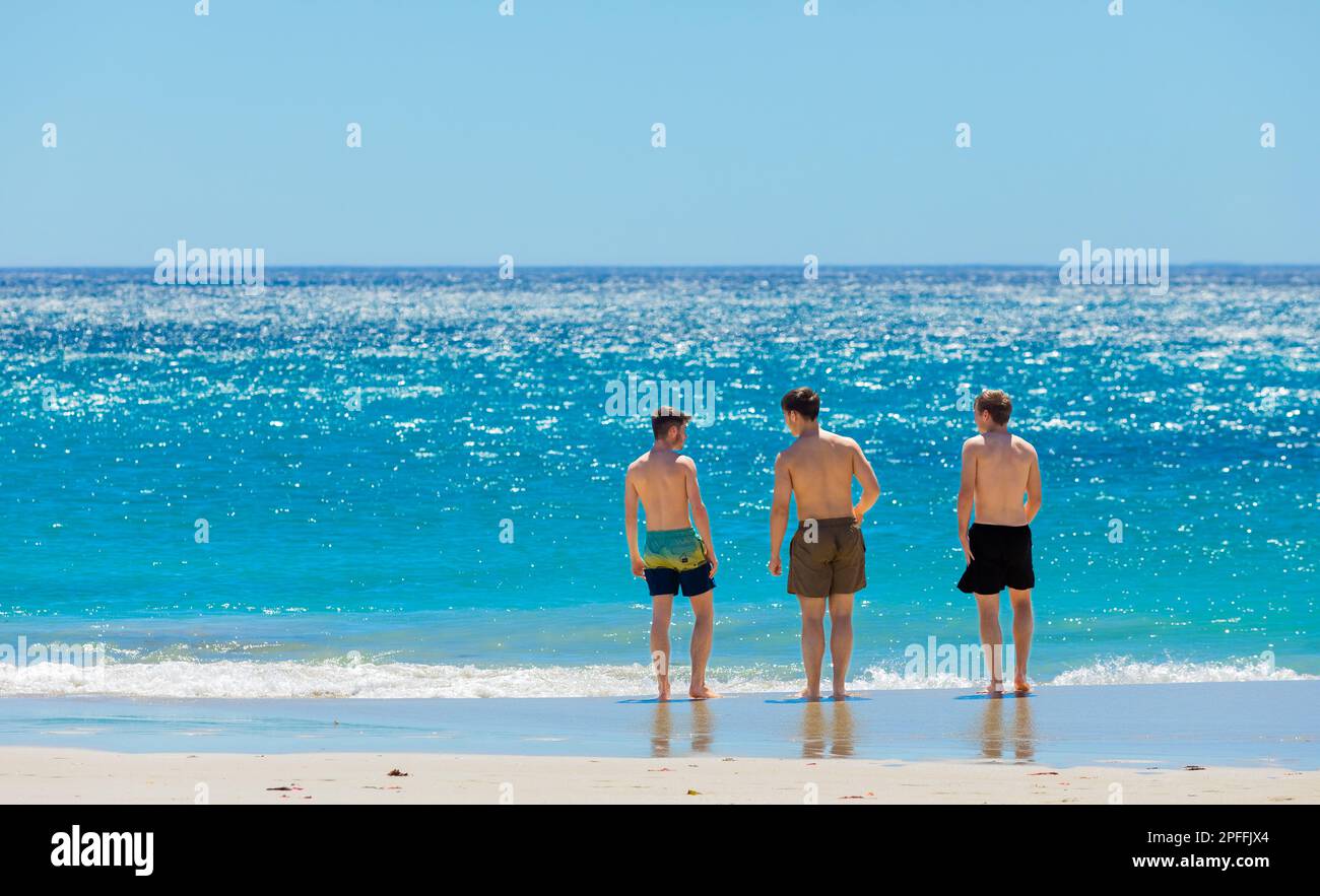 Cape Town, South Africa - February 18, 2023: Young male vacationers on Camps Bay beach Stock Photo