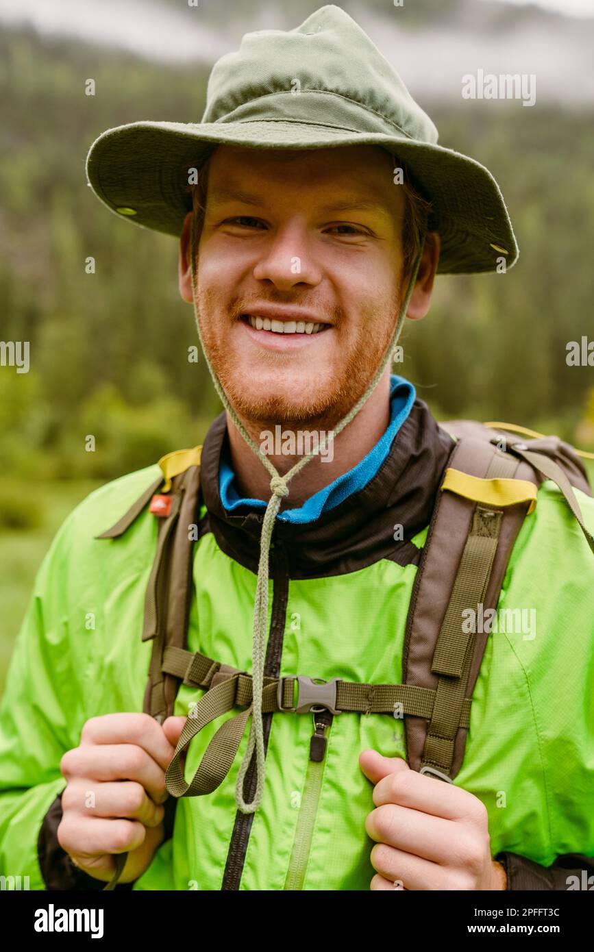Young man tourist with backpack smiling at camera during hiking in mountains Stock Photo