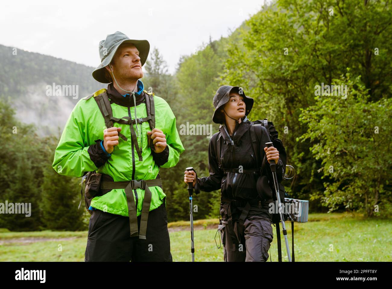 Young white people wearing trekking equipment hiking in mountain forest Stock Photo