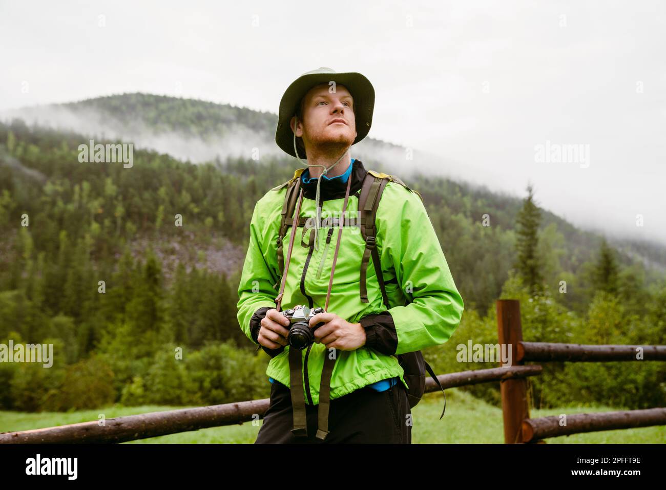 Young white man wearing trekking equipment using camera while hiking in mountain forest Stock Photo