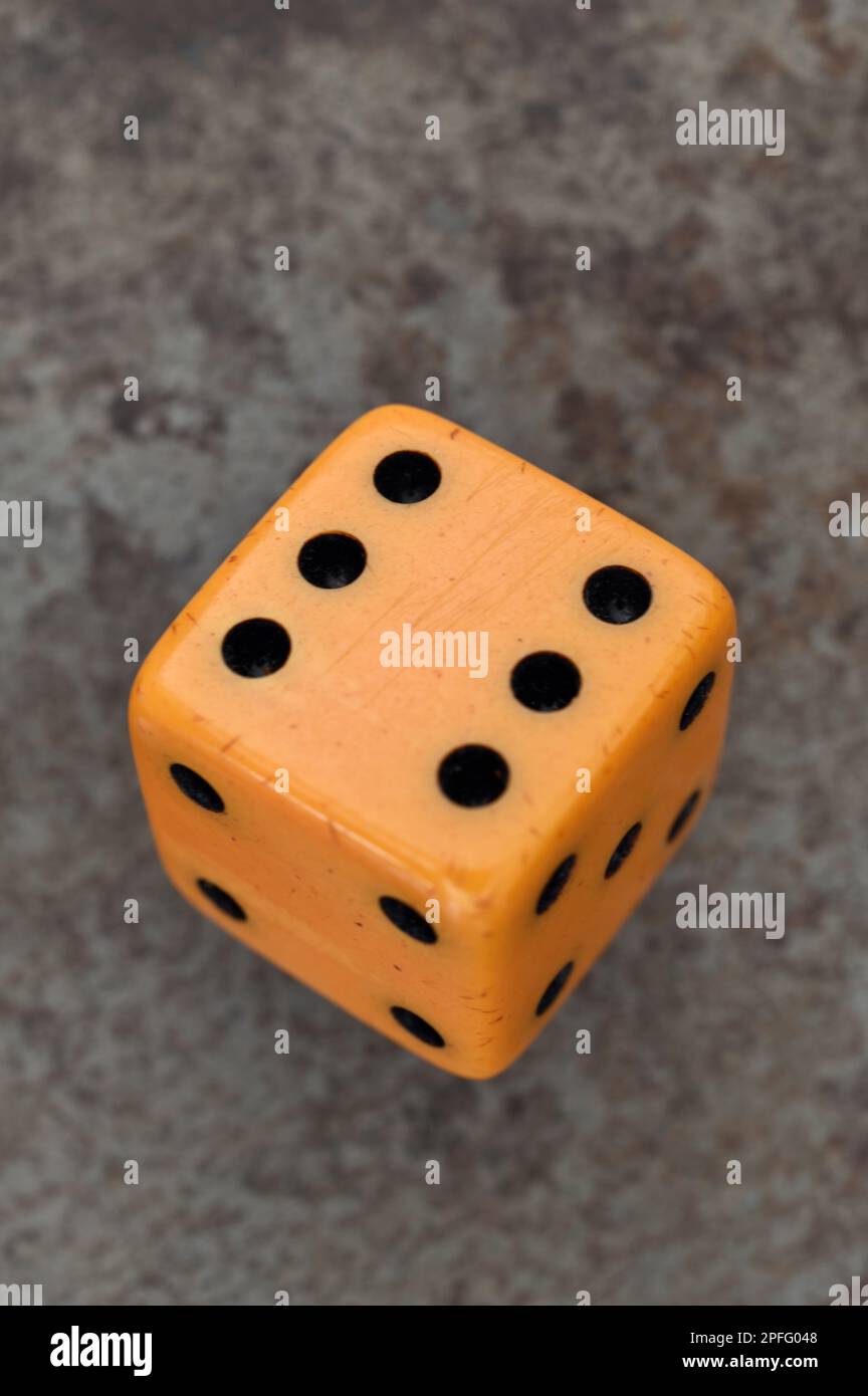 Single vintage ivory dice lying on tarnished metal with six facing