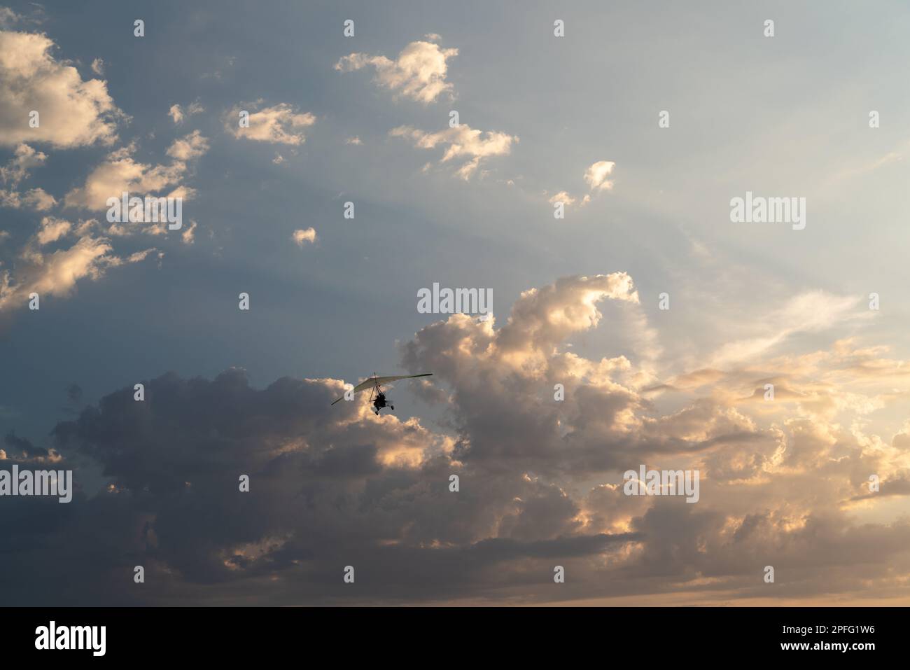 Propeller plane flies in the sunset sky. A small private hang-glider in ...