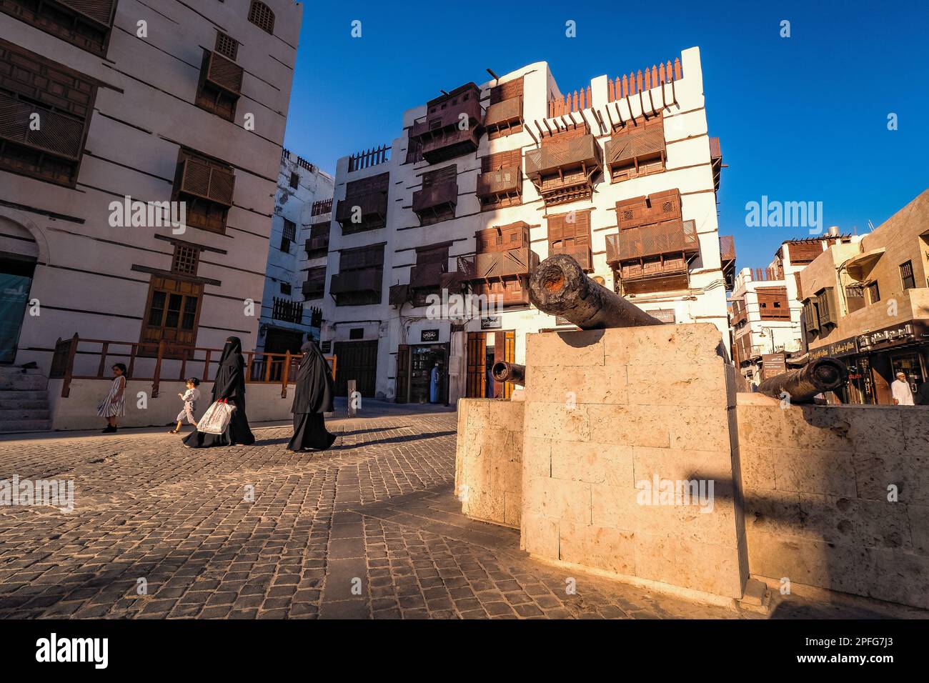 View of Arab women in abaya with children passing the cannon at Souk al Alawi Street in the historic district of Al-Balad, Jeddah, KSA, Saudi Arabia Stock Photo