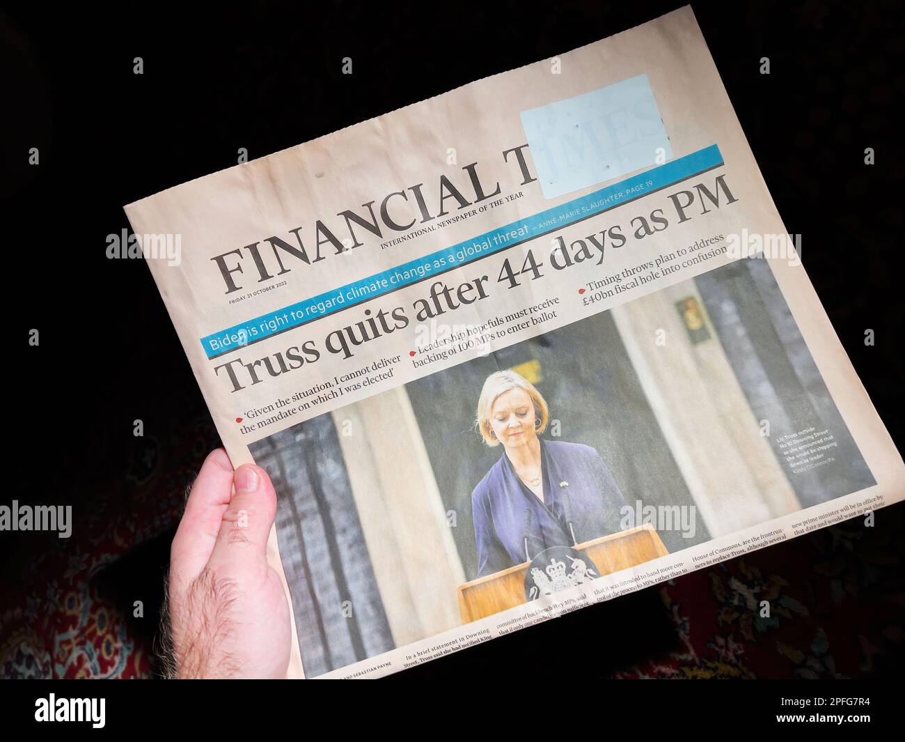 LONDON, ENGLAND - OCTOBER 20: Male hand reading Financial Times announcing the resignation of Prime Minister Liz Truss, in Westminster - a black background, featuring the latest headlines and important international political news from Europe and Britain. Stock Photo