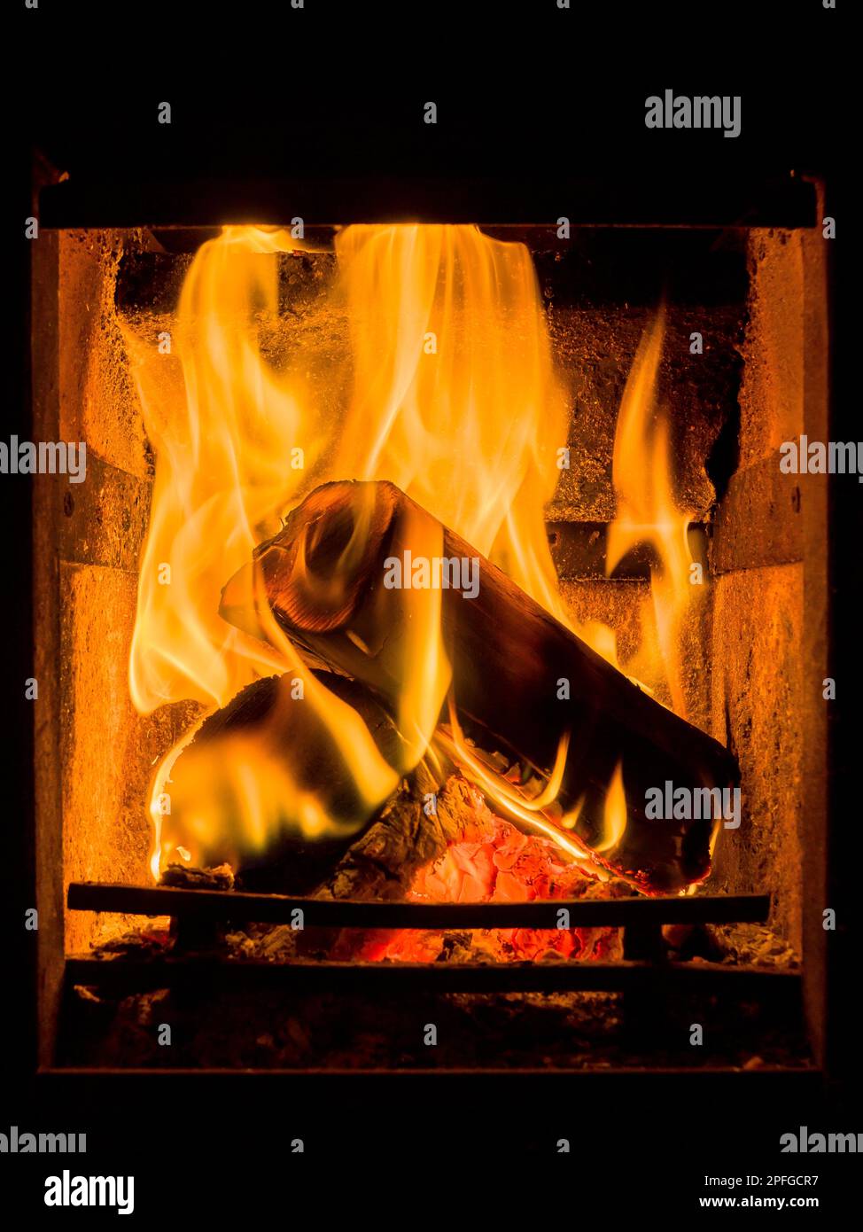 Logs burning in an open fireplace in a domestic home in winter. Stock Photo
