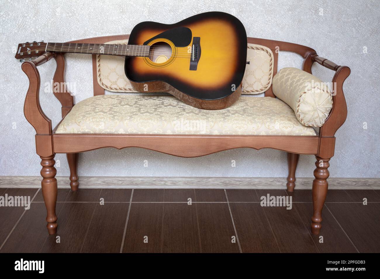 Beautiful classical seven-string guitar on a small sofa against the wall in  the living room with natural light Stock Photo - Alamy