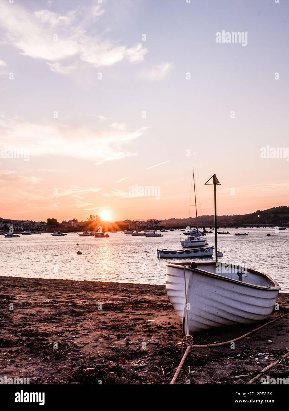 A Vertical Shot Of A Boat On A Beach During The Sunset In Teignmouth A Vertical Shot Of A Boat On A Beach During The Sunset In Teignmouth
