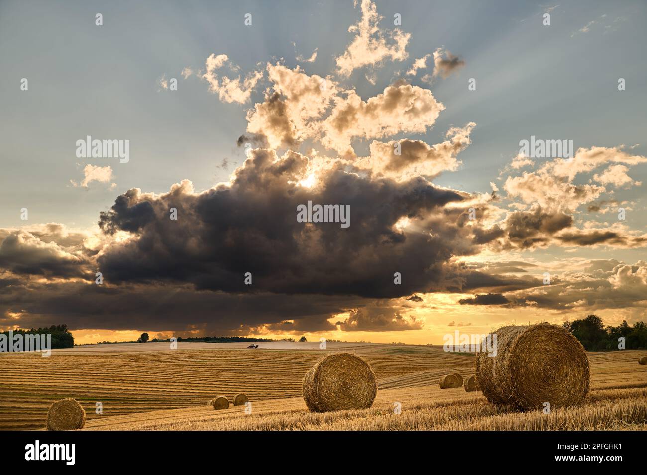 Field landscape after harvest with spectacular sky and passing tractor ...