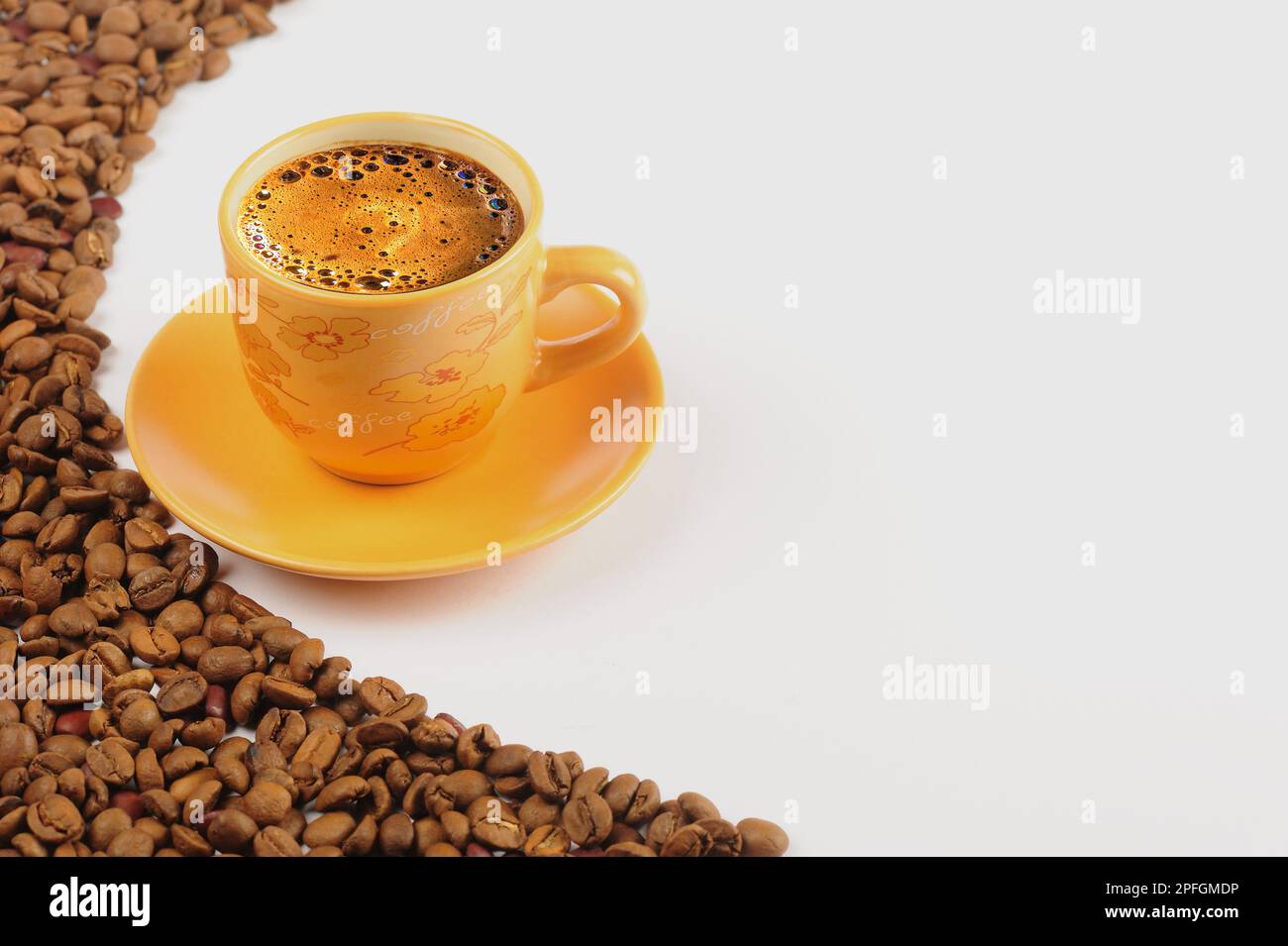 frothy turkish coffee in yellow cup beside coffee beans and white background Stock Photo