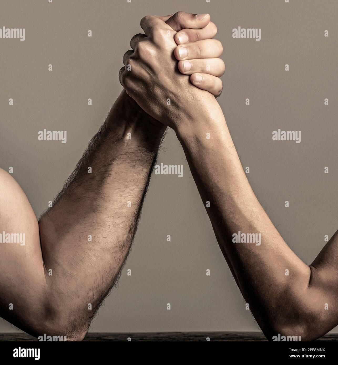 Two man's hands clasped arm wrestling, strong and weak, unequal match