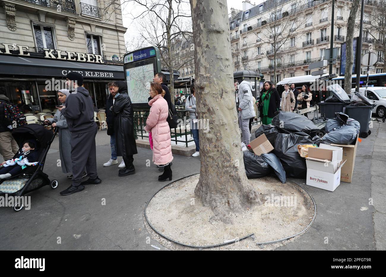 Paris, France. 17th Mar, 2023. People wait outside a restaurant at Trocadero place while garbage is seen on the street in Paris, France, March 17, 2023. Garbage is likely to continue accumulating in the capital, since refuse collectors and street cleaners will be on strike until March 20. Credit: Gao Jing/Xinhua/Alamy Live News Stock Photo