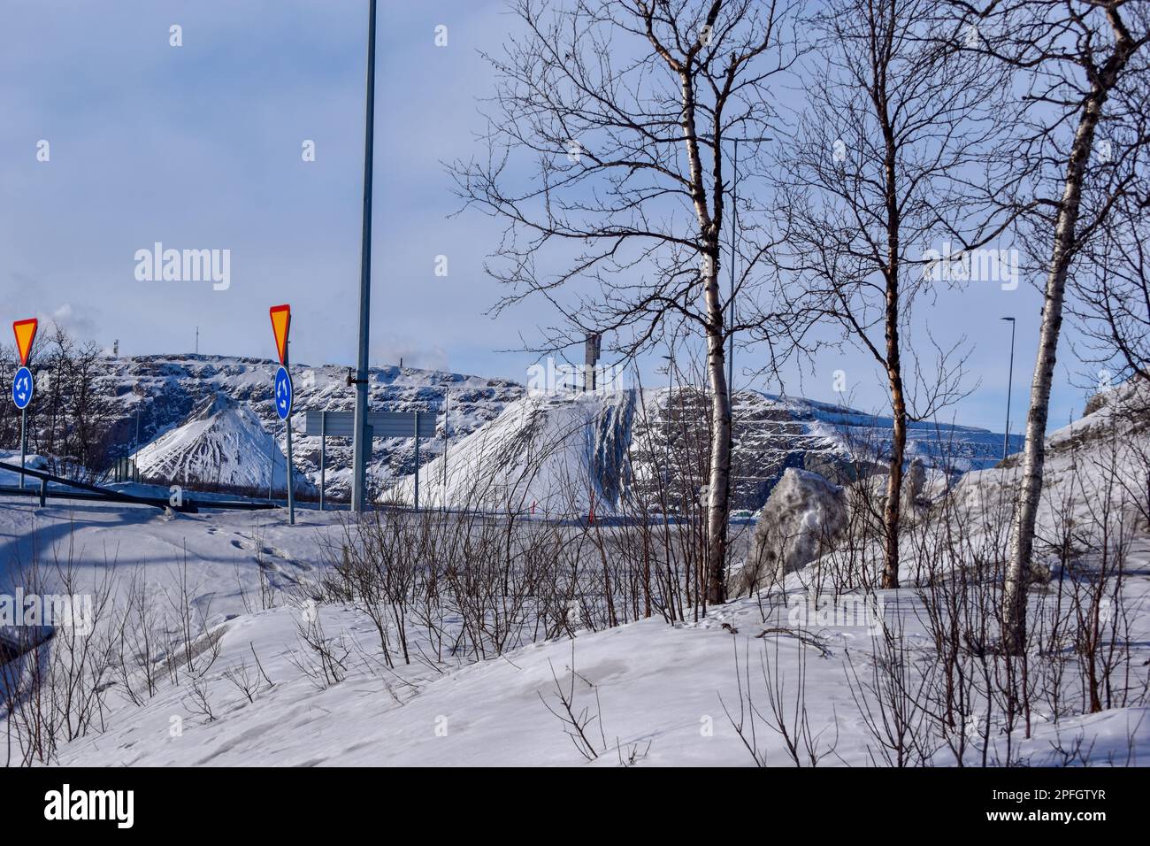 View of Kiruna city and the iron ore mine on the mountain Kiirunavaara seen from the snowy mountain peak Luossavaara. Stock Photo