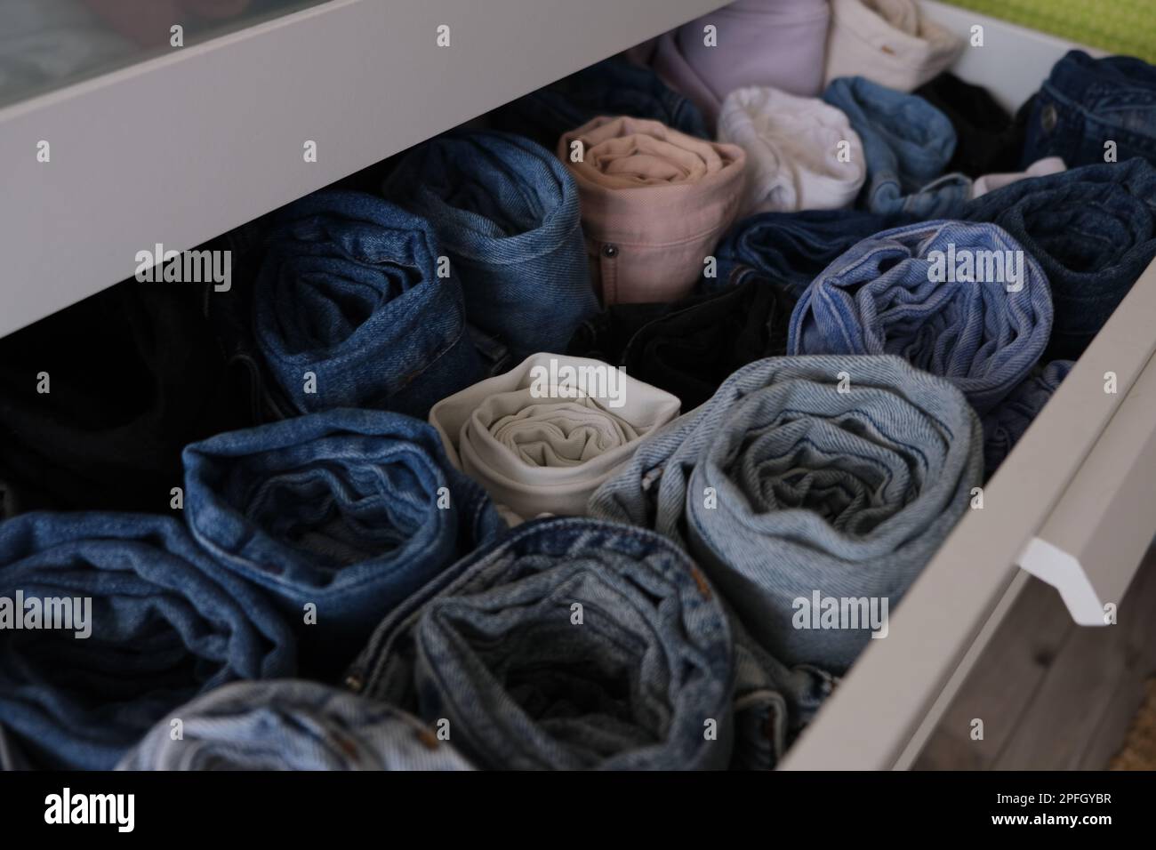 Drawer full of denim jeans, open drawer with folded blue, white, pink