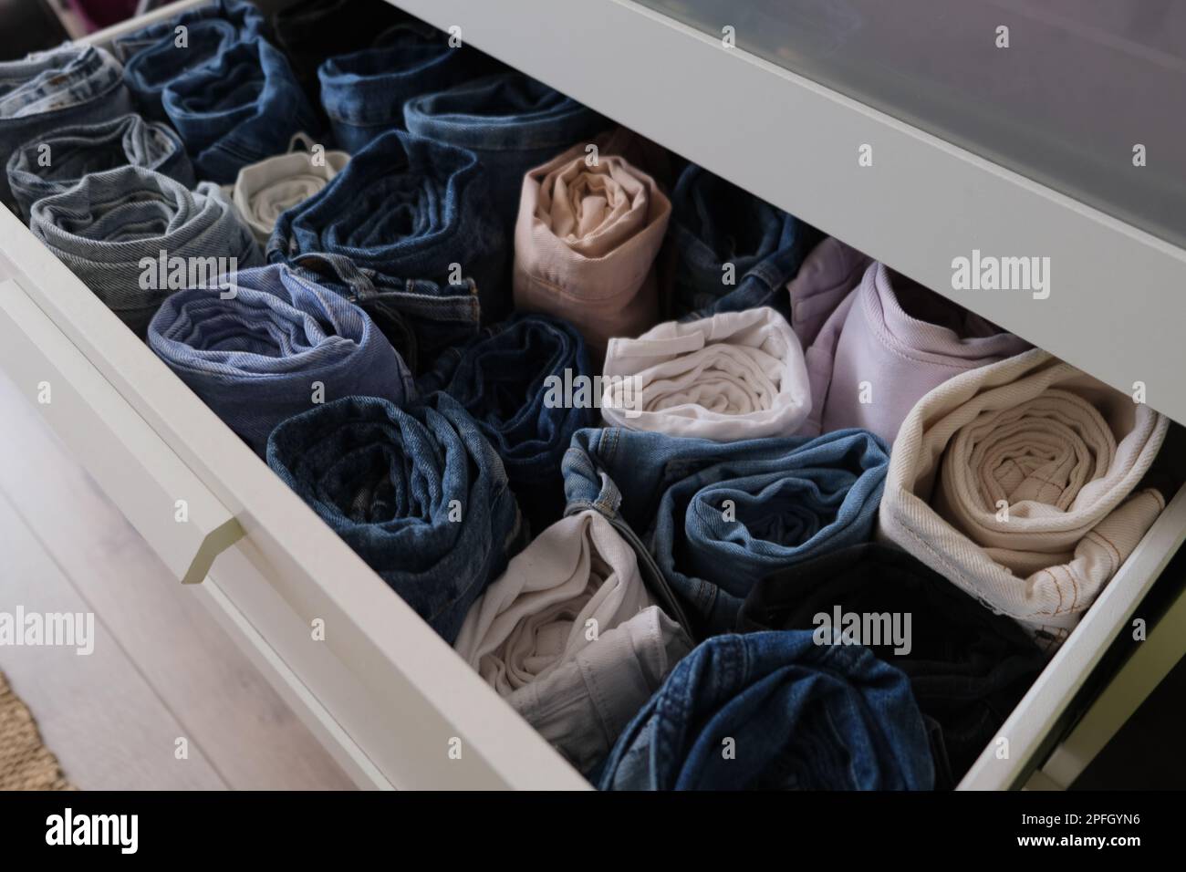Drawer full of denim clothes, near open drawer with folded denim jeans