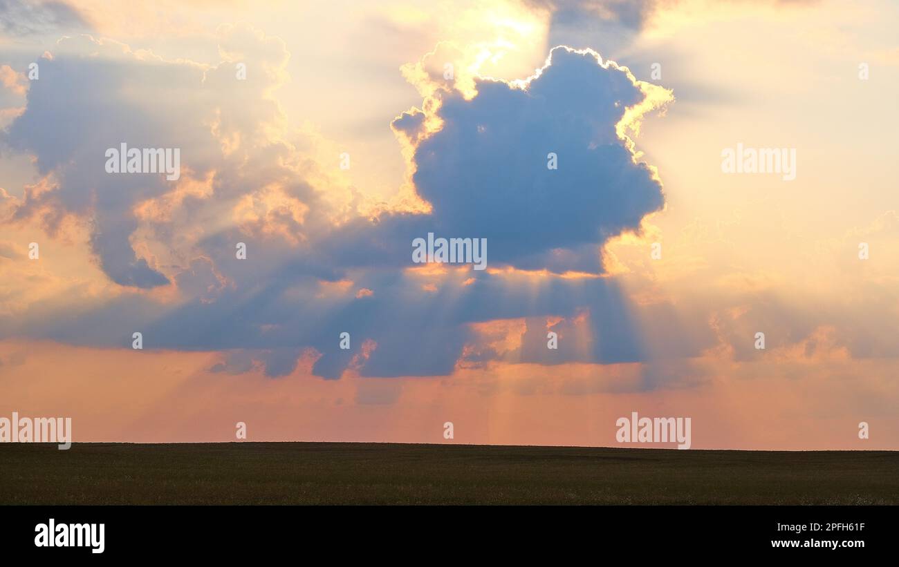 sunset, the rays of which break through the clouds creating a silhouette and contour of the clouds Stock Photo