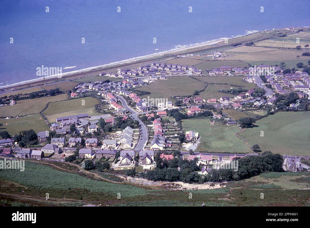 1964, historical, aerial view over the coastal town of Penmaenmawr, Conwy, Wales, as seen from the high mountain, which the town is named after. Stock Photo