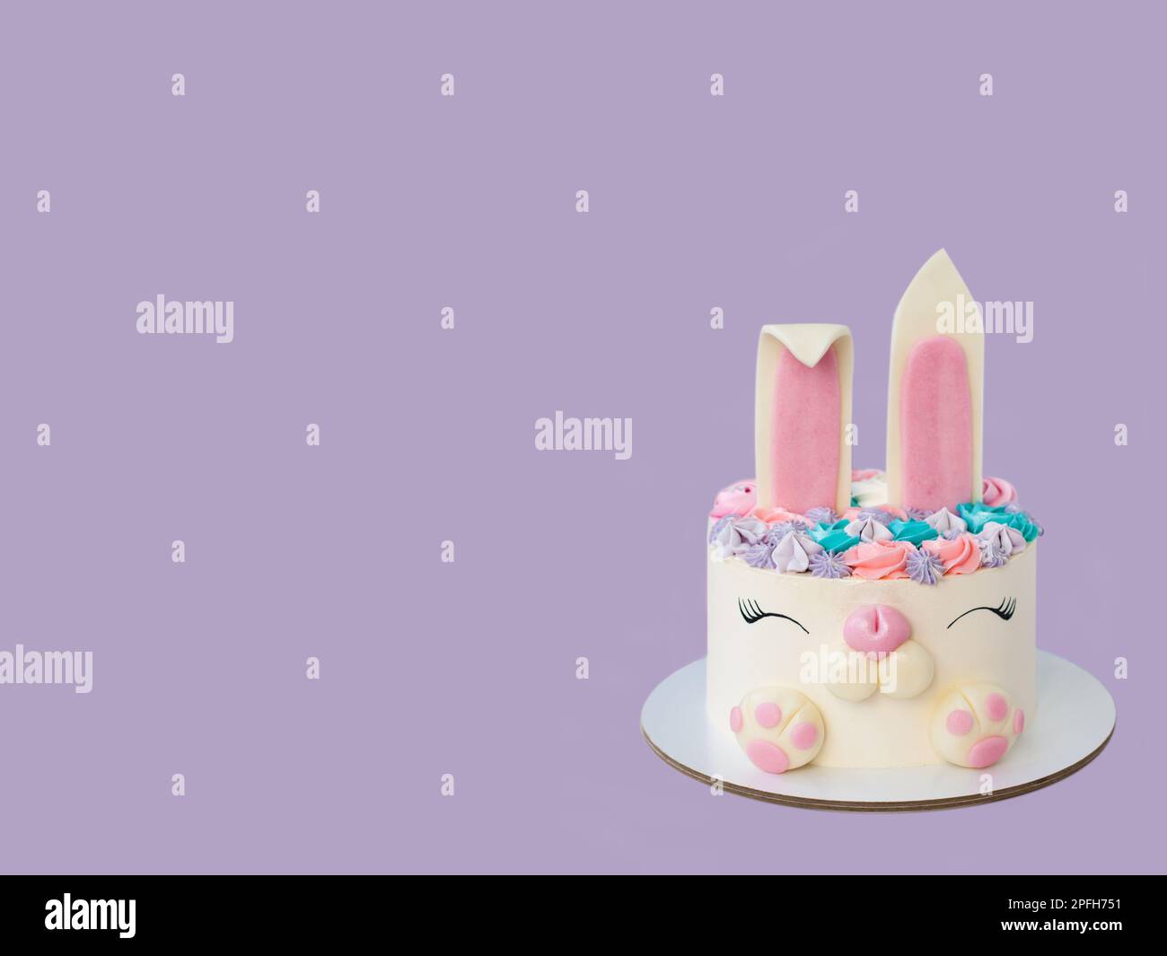 White and pink cake with cute bunny for children's birthday or Easter. Purple background. Horizontal orientation Stock Photo