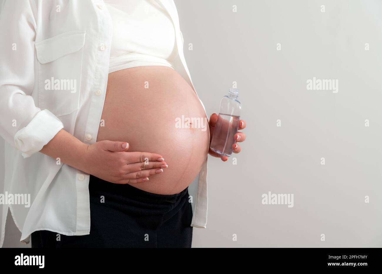 Pregnant woman applying cosmetic oil on her belly for healing stretch