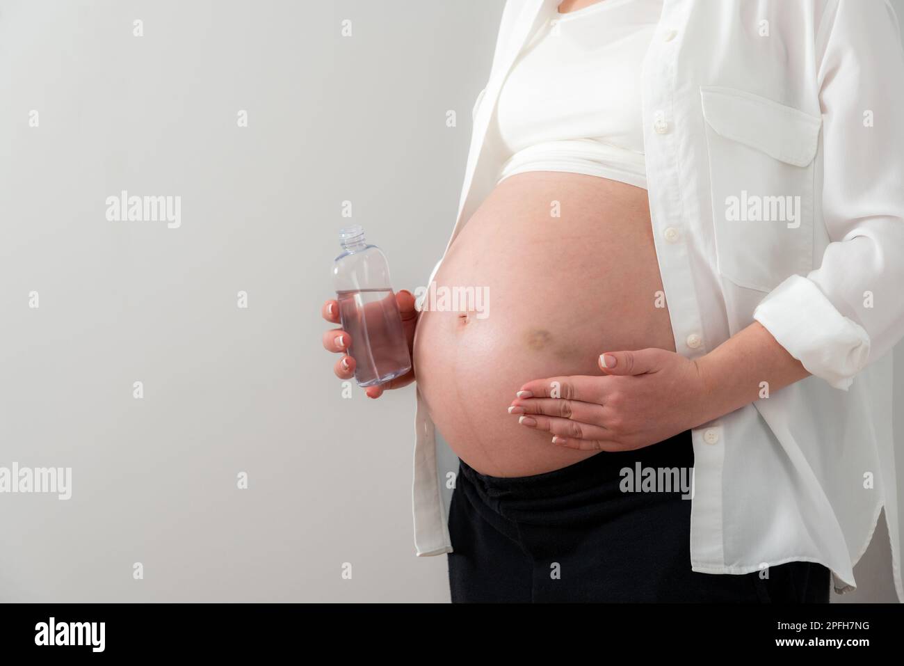Pregnant woman applying cosmetic oil on her belly for healing puncture
